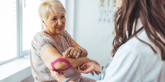 Chiropractor helping older woman with elbow